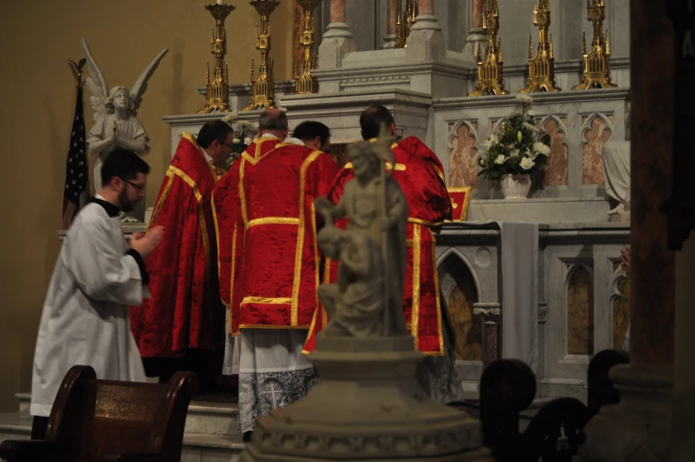 several men dressed in red and yellow robes stand at the altar