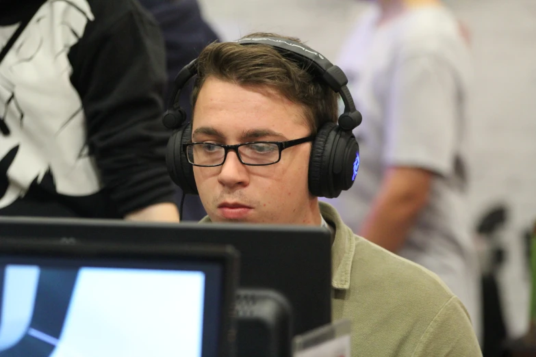 young man with headphones sitting in front of computer monitor