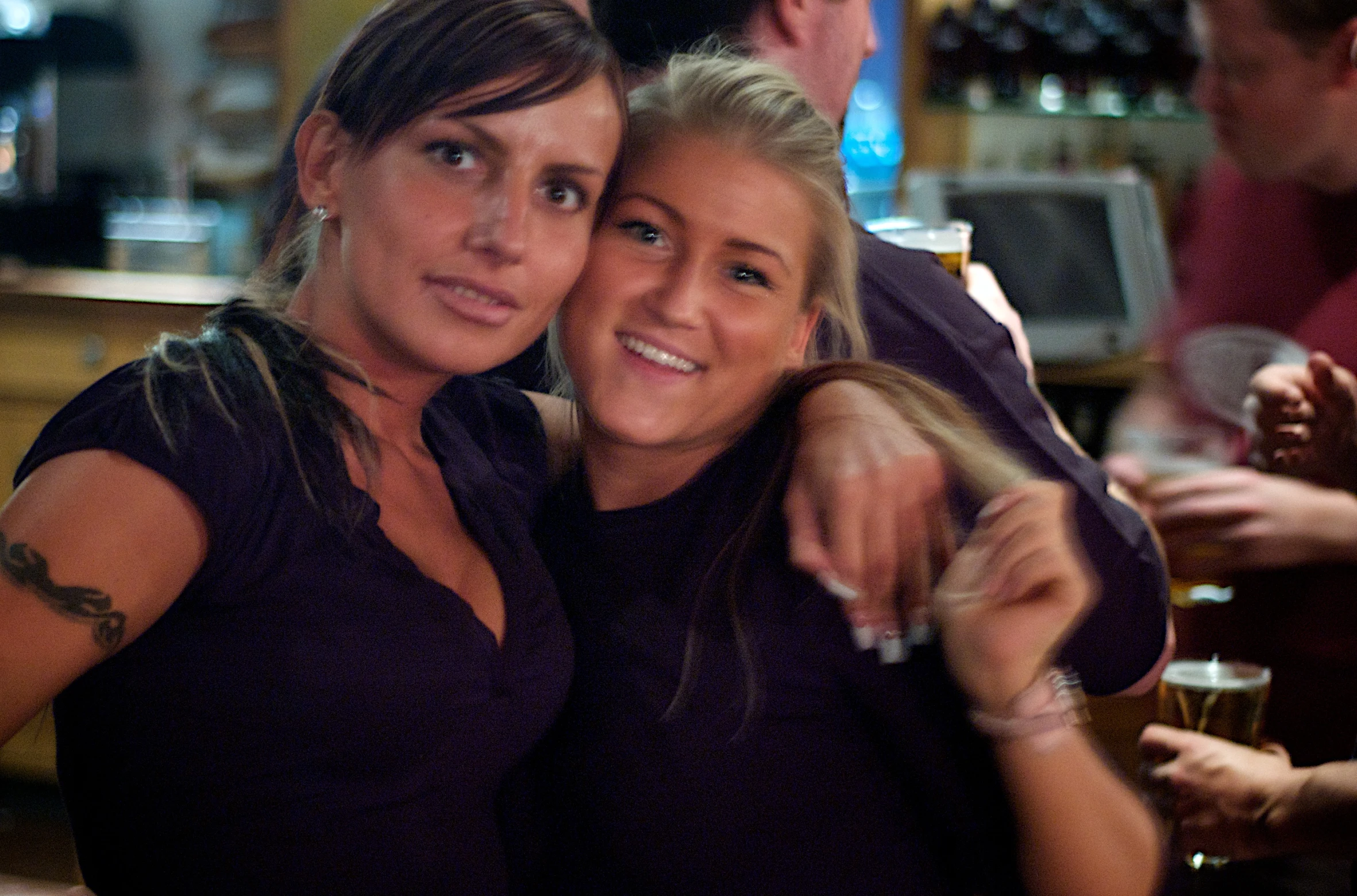 two beautiful women hugging each other in a bar