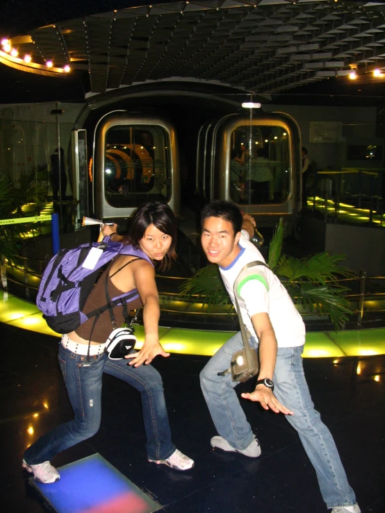 two friends are posing for a picture in front of a train