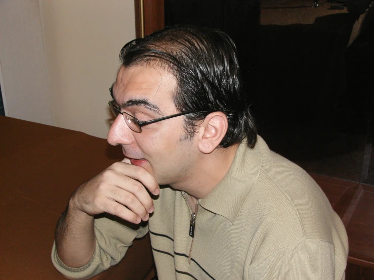 a man in glasses sitting at a wooden table