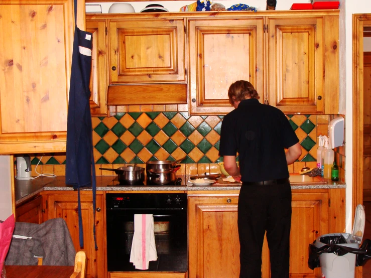 the man is standing in the kitchen preparing some food