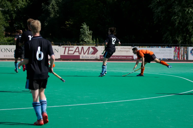 two boys wearing red socks and orange shirts playing field hockey