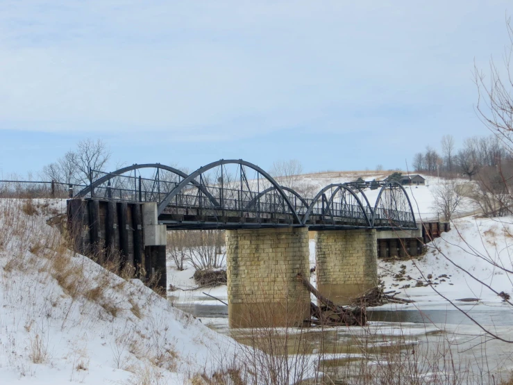 a train bridge over snow covered river near a snowy landscape