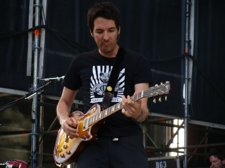 a male in a black shirt is playing a guitar