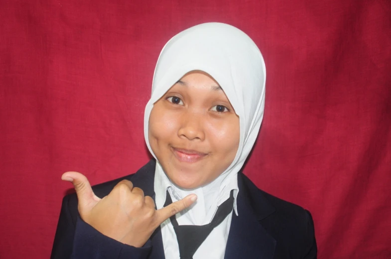 a young woman wearing a hijab and pointing