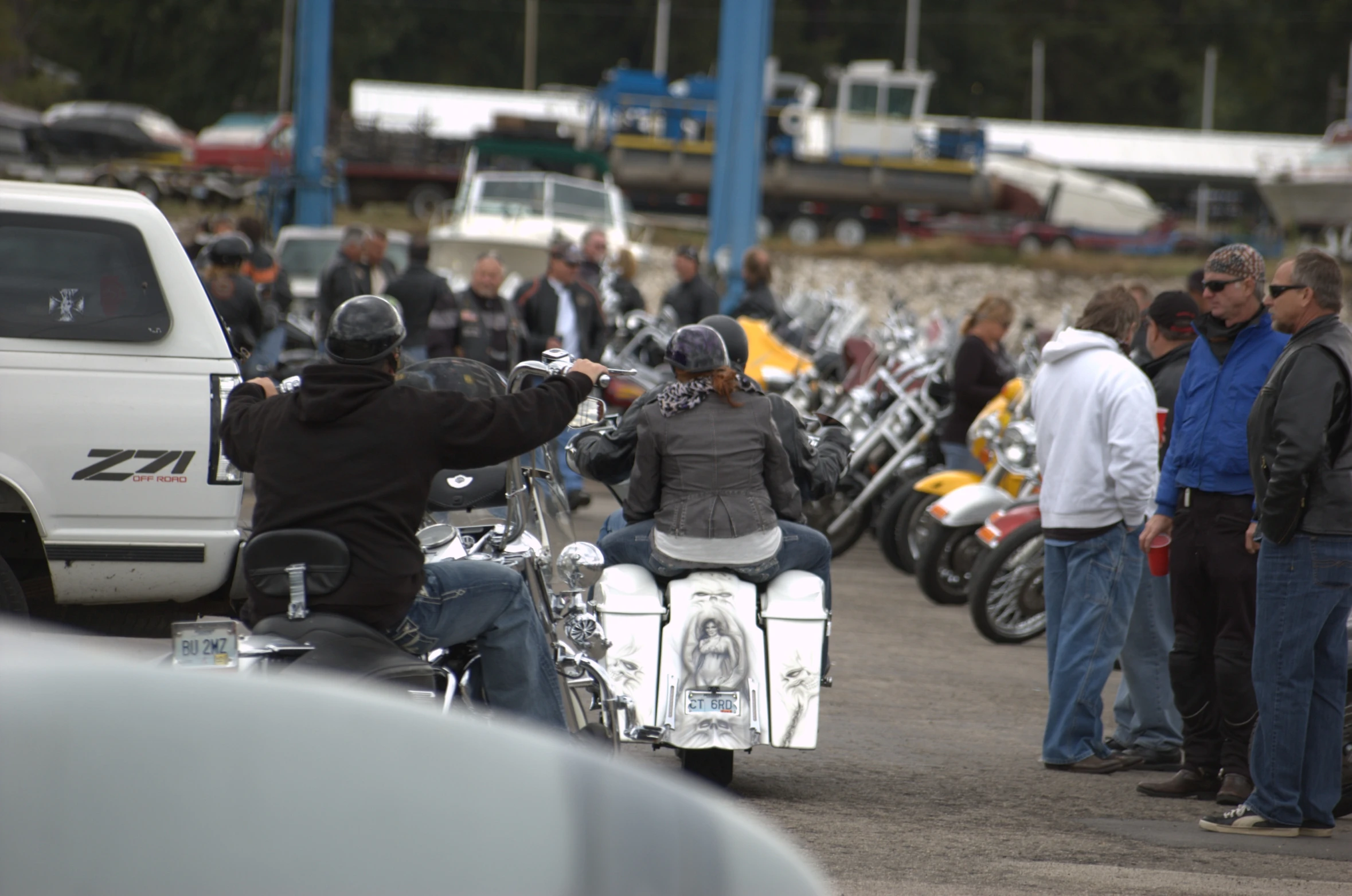 motorcyclists are standing near parked motorcycles on display