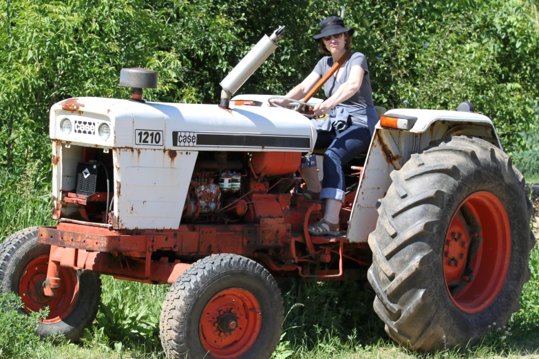 a woman sitting on top of an old tractor in a field