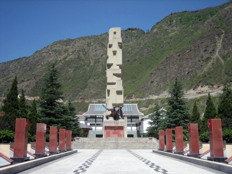 statue in middle of outdoor area with trees near hill