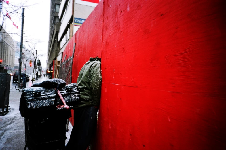 there is a black backpack leaning on a red wall