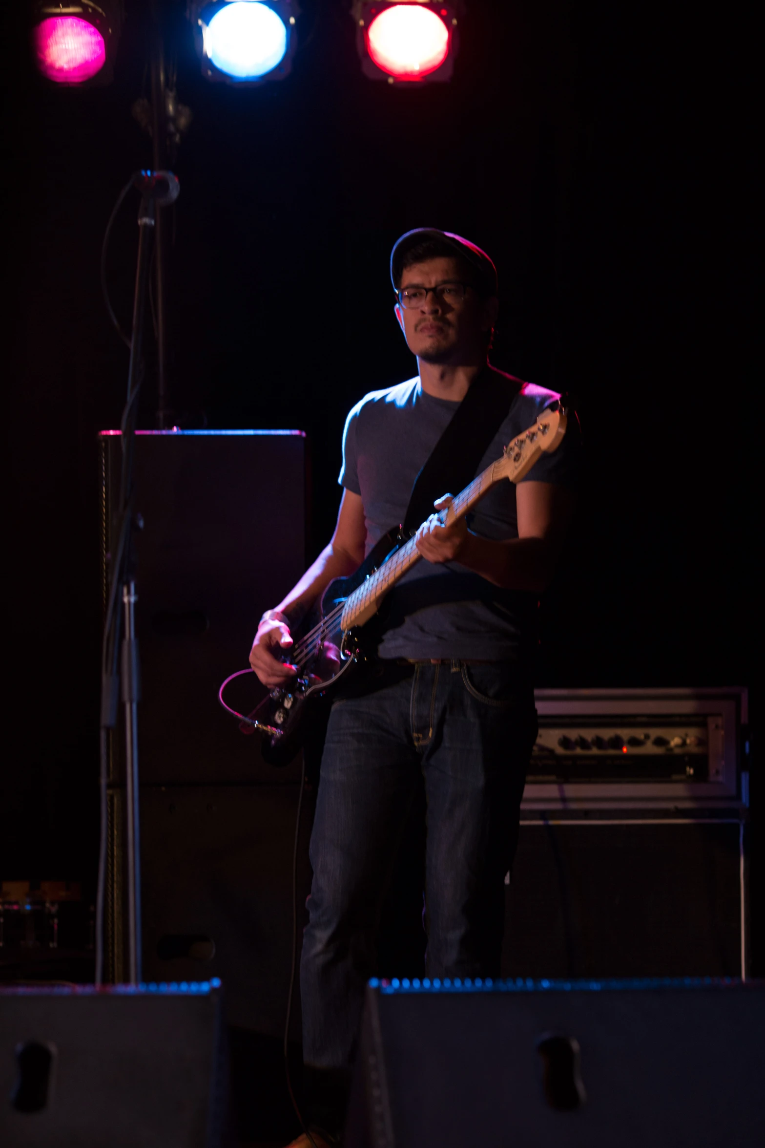 a man holding a guitar in his right hand and some lights in the background