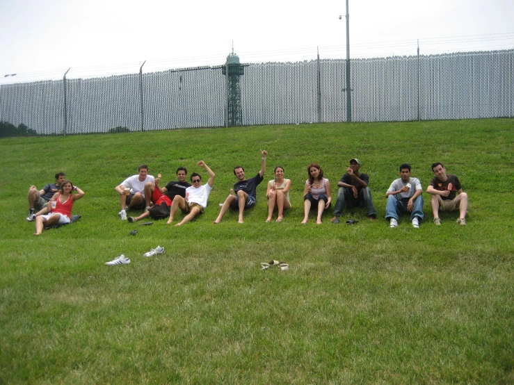 several people sit in the grass with one woman standing, one man sitting