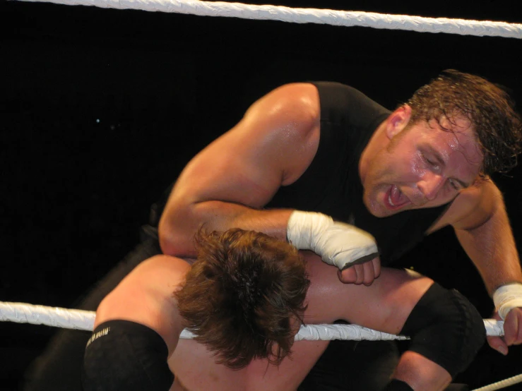 two men wrestling inside of a ring and one is holding his hand out