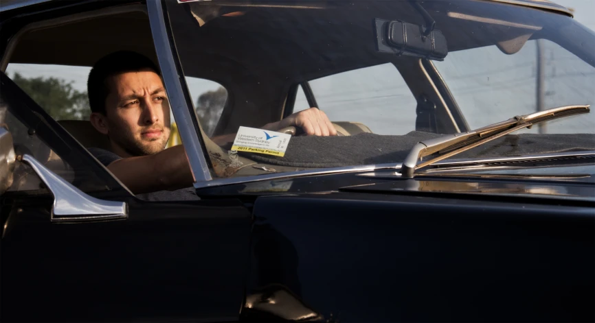 a man in his car holding the steering wheel with his hand