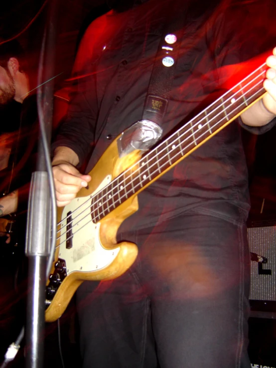 a man playing a bass guitar in front of red light
