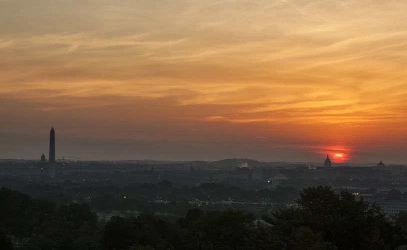 the setting sun rises above a city skyline