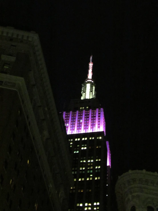 night view of the empire state building, with the empire tower lit up in purple