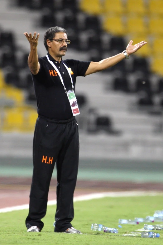 a male in a black shirt standing on a soccer field