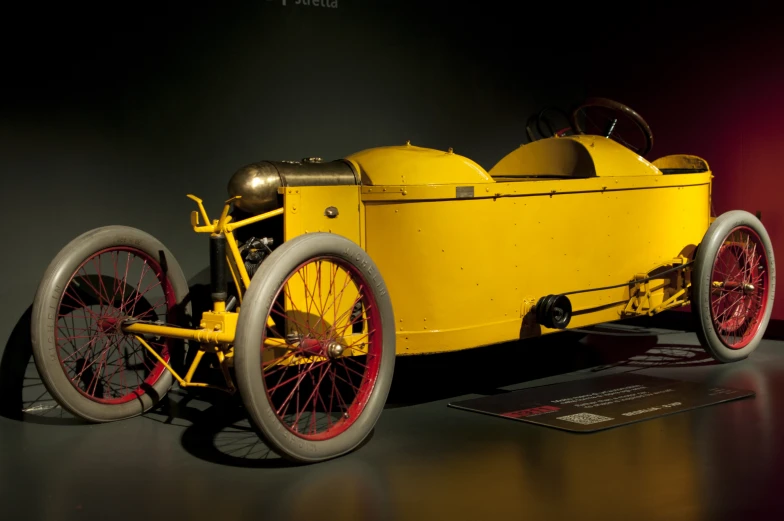 an old yellow pedal car sitting in a museum