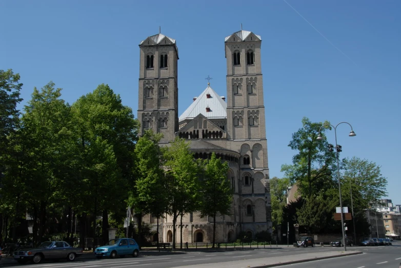 a view of an old church across the street from cars parked in front of it