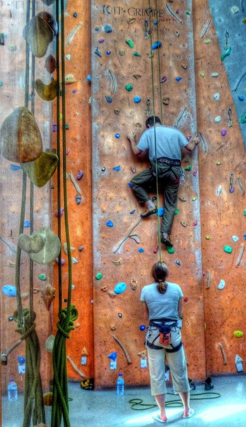 two people are climbing up an indoor climbing wall