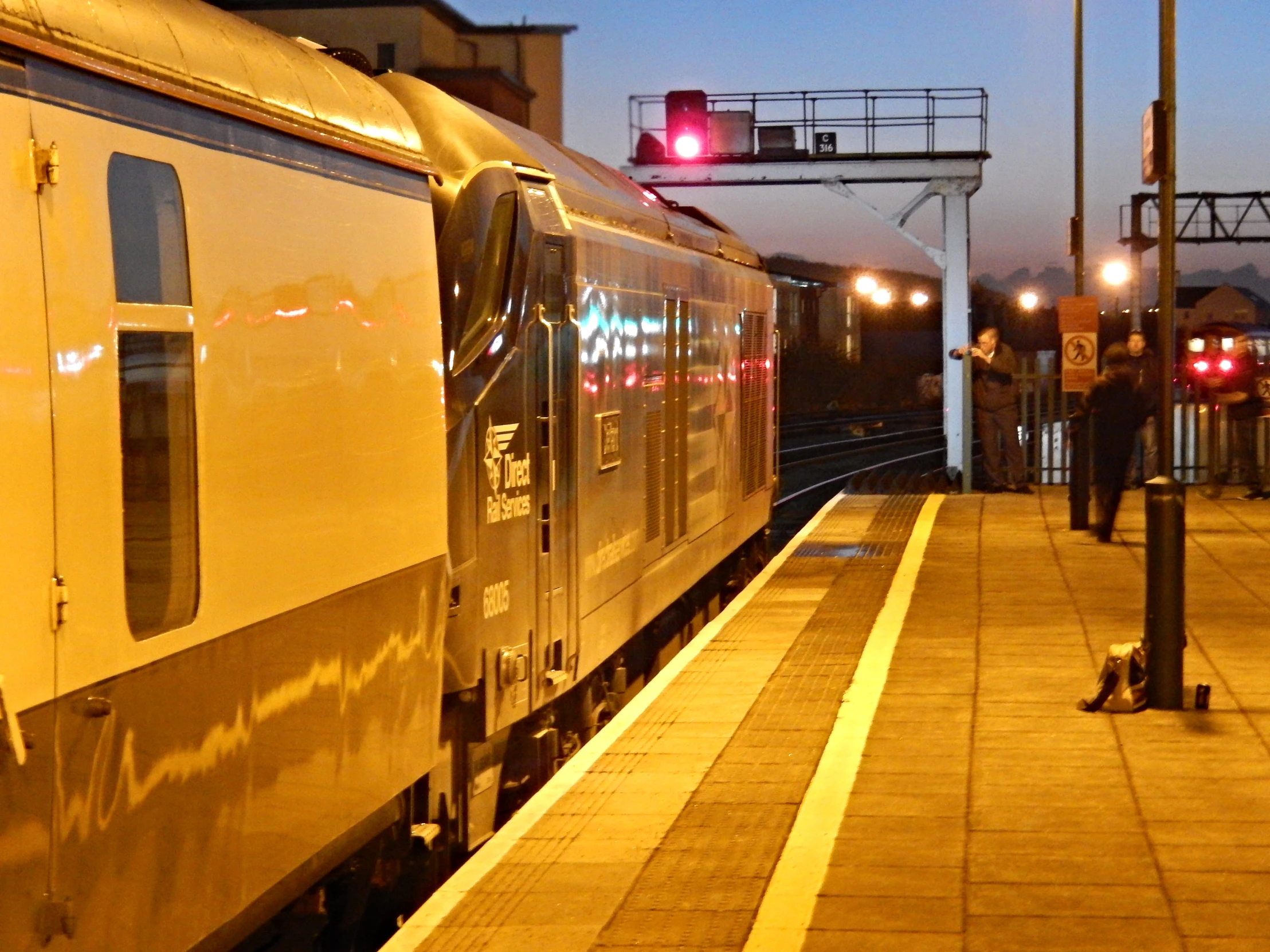 the train is stopped at the station with its lights on