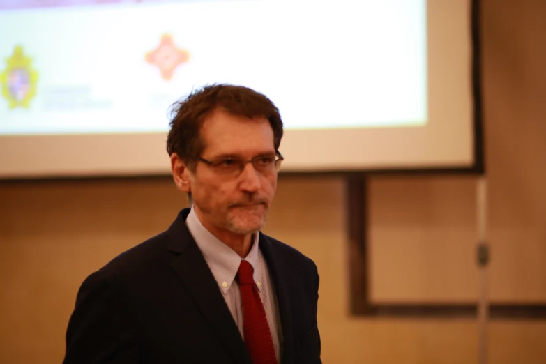 man in a suit standing in front of screen