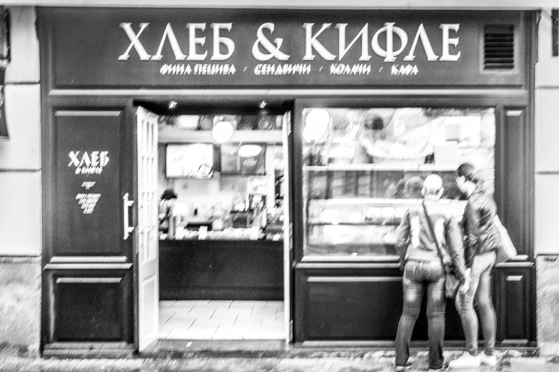 a couple standing on the side of a road next to a store