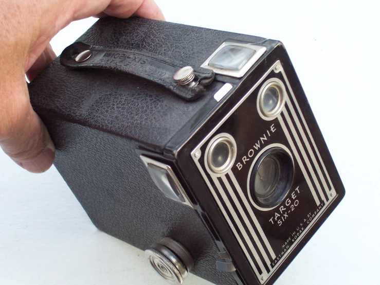 an old camera sitting on a table with a person holding it