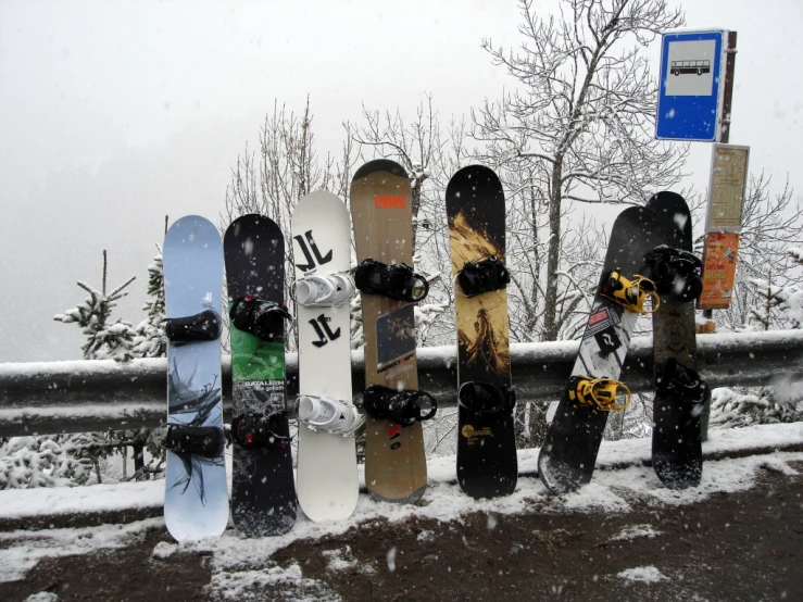 several snowboarders are standing next to a snowy fence