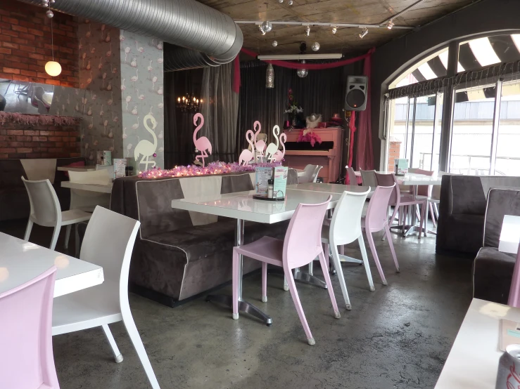 a fancy restaurant with tables and chairs is decorated with pink, white and grey flamingos