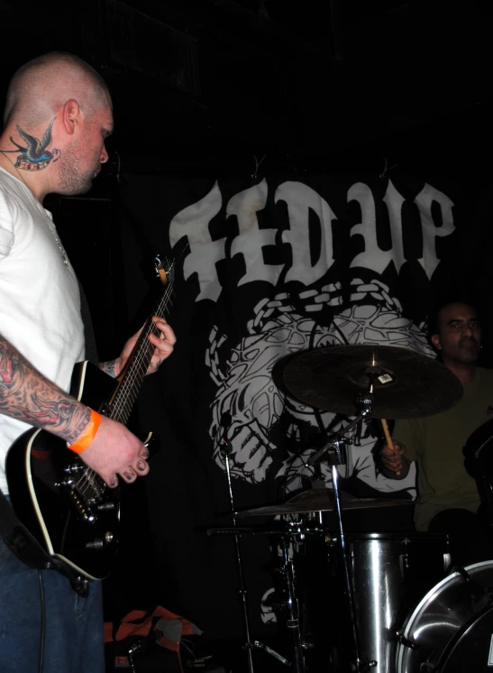 a bald man in black pants playing guitar