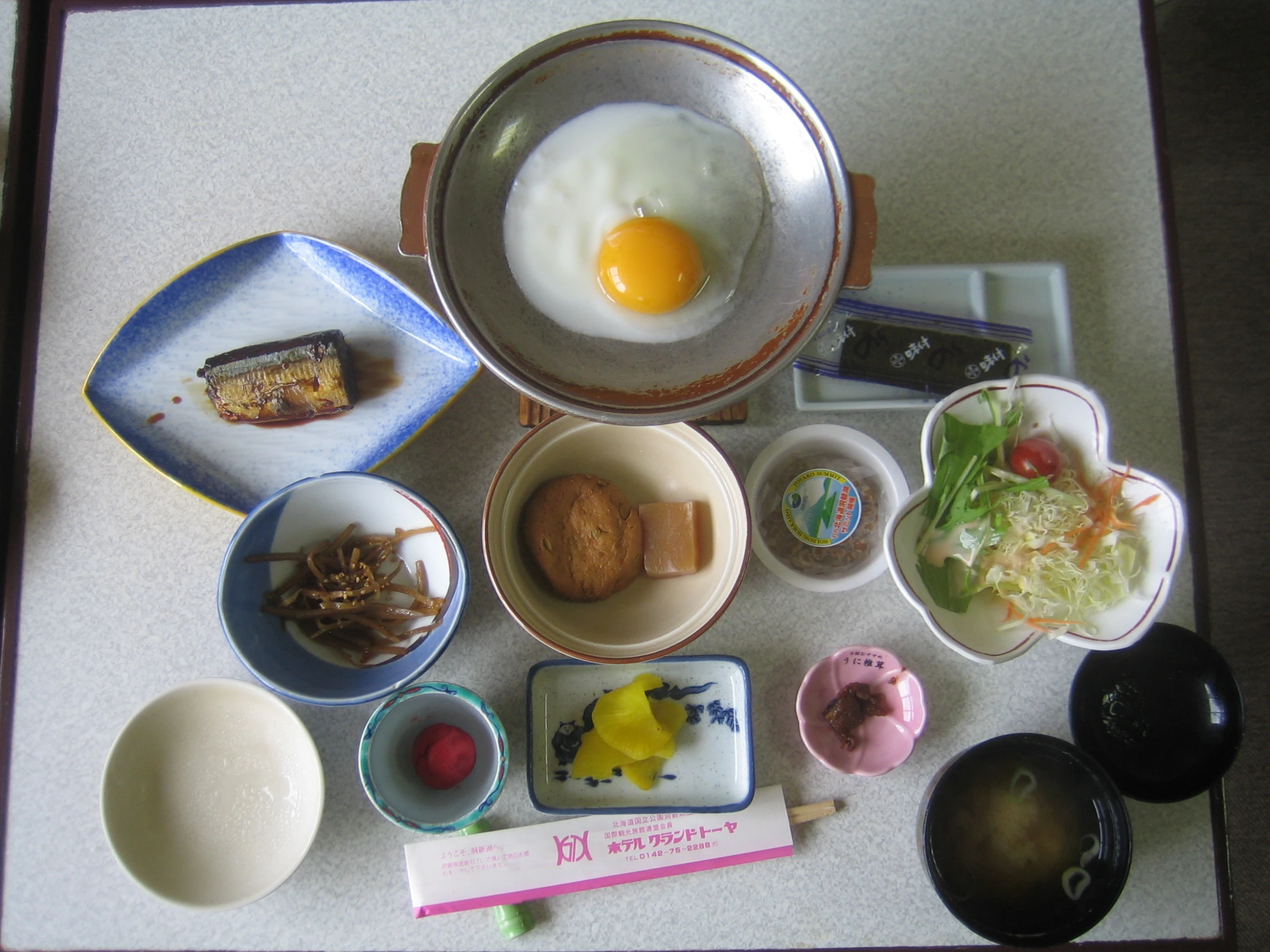 a table with many bowls of food and one egg