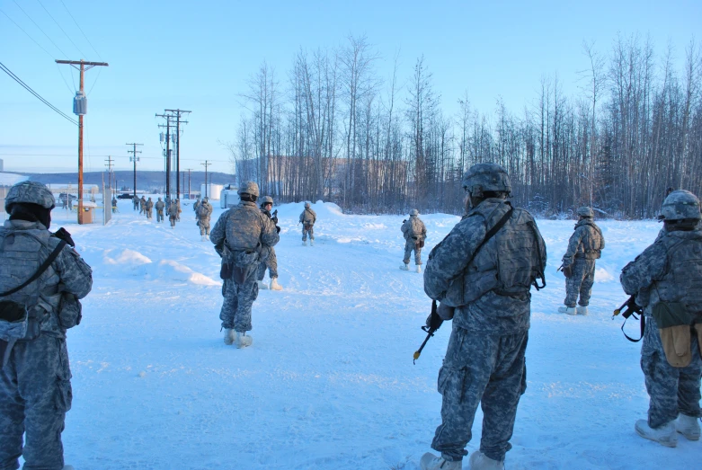 soldiers walk across snow covered ground near telephone poles