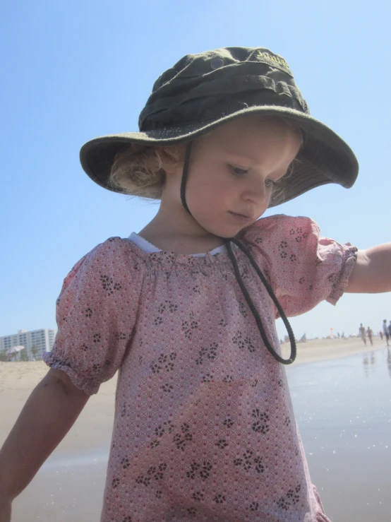 a  walking along a beach wearing a sun hat