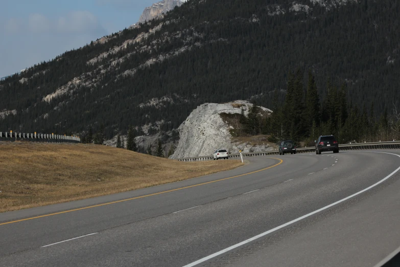 cars going down a road with mountains in the background