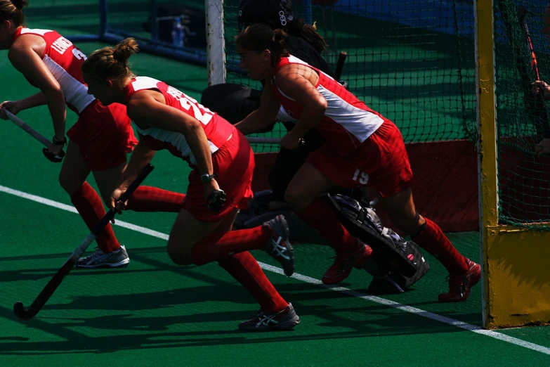 female hockey players race after the ball as they play