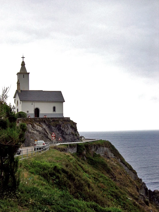 the lighthouse has a steeple in front of it and the ocean is also around