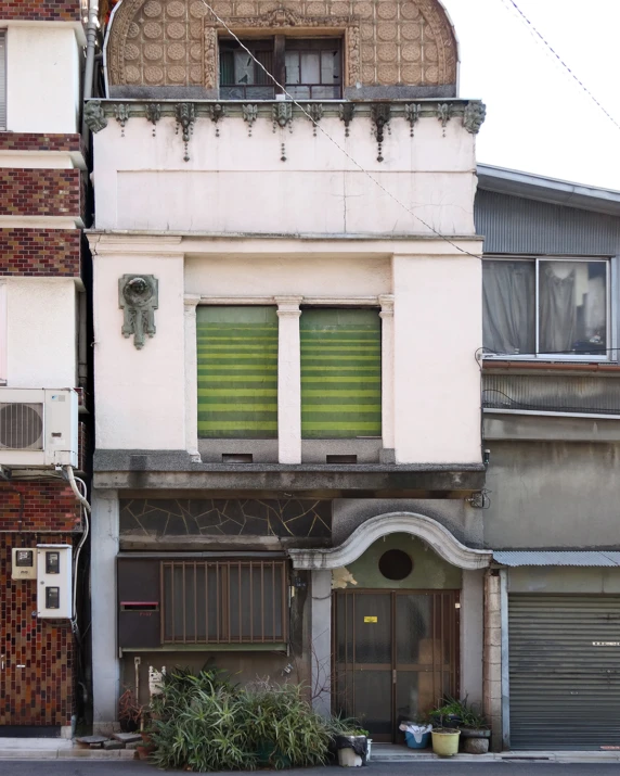 the building has a green door outside the shutters