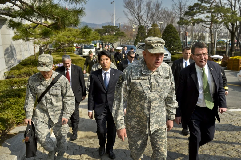 several people in suits walking with some wearing military uniforms
