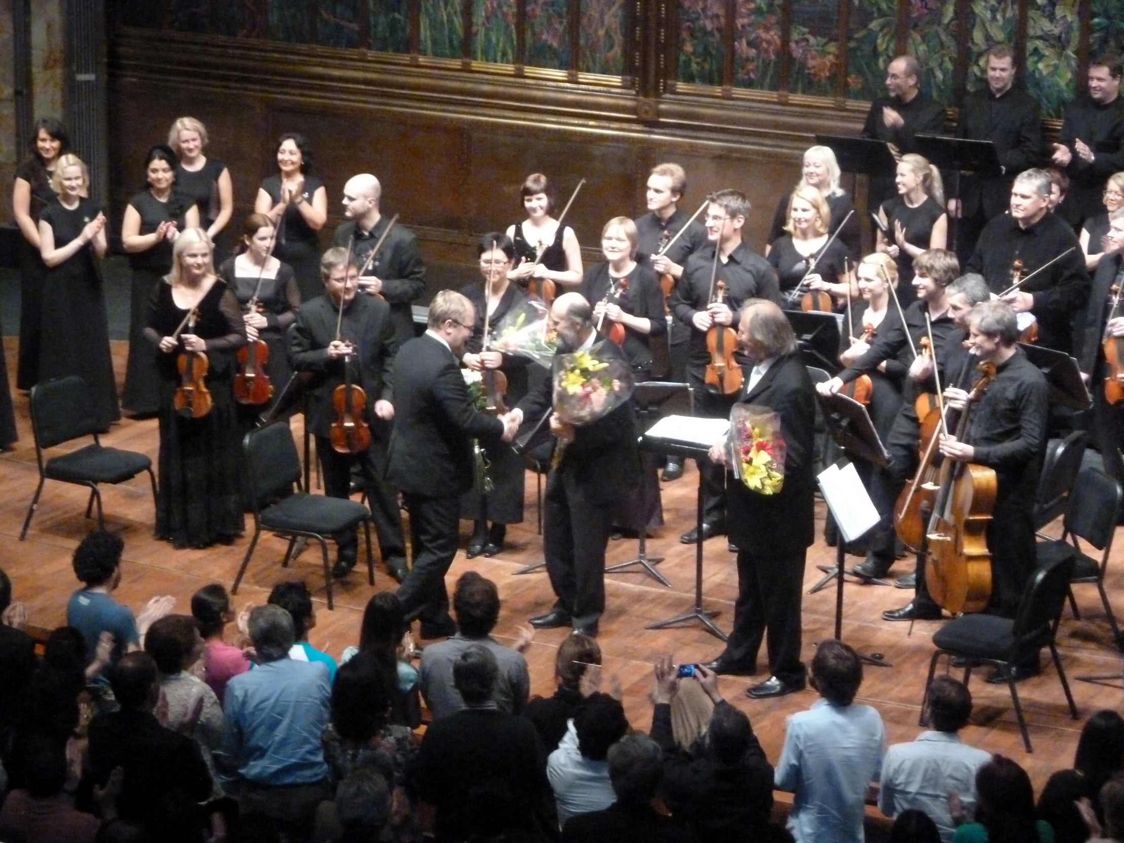 orchestra members perform on stage with conductor