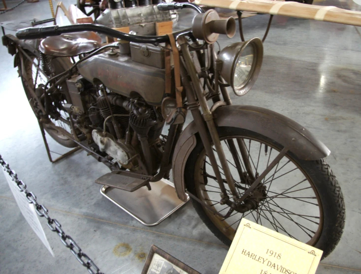 old model motorcycle displayed on cement floor with chain linked area