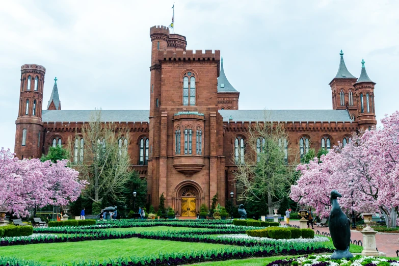 a large brick building surrounded by a green and white garden