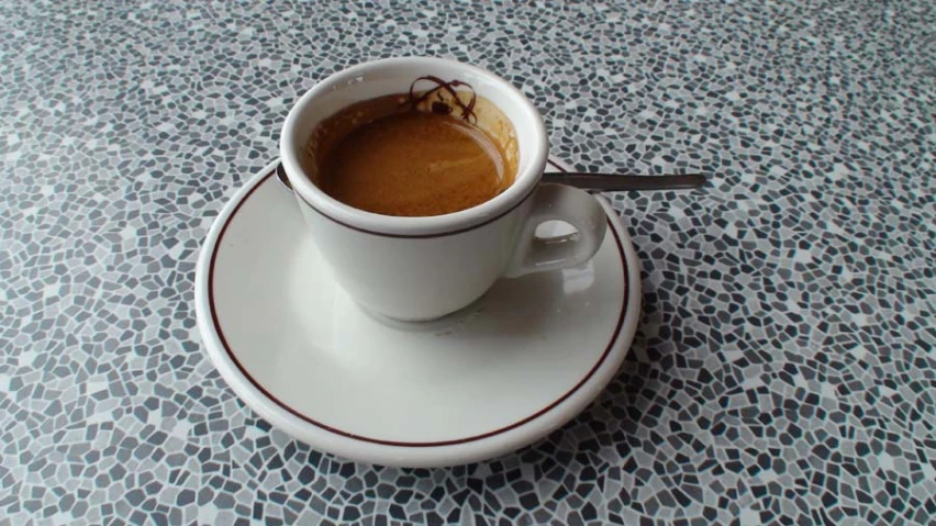 coffee is served in a cup on a saucer with a spoon