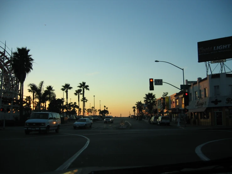 a street at twilight with cars and palm trees