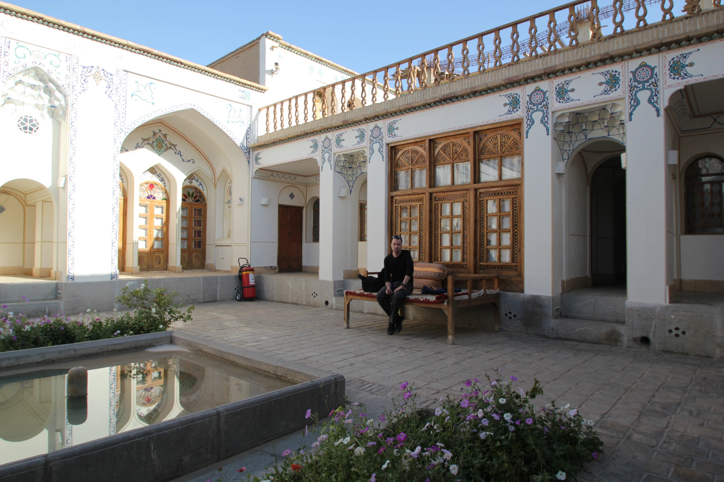 a man sits outside a house with a fountain