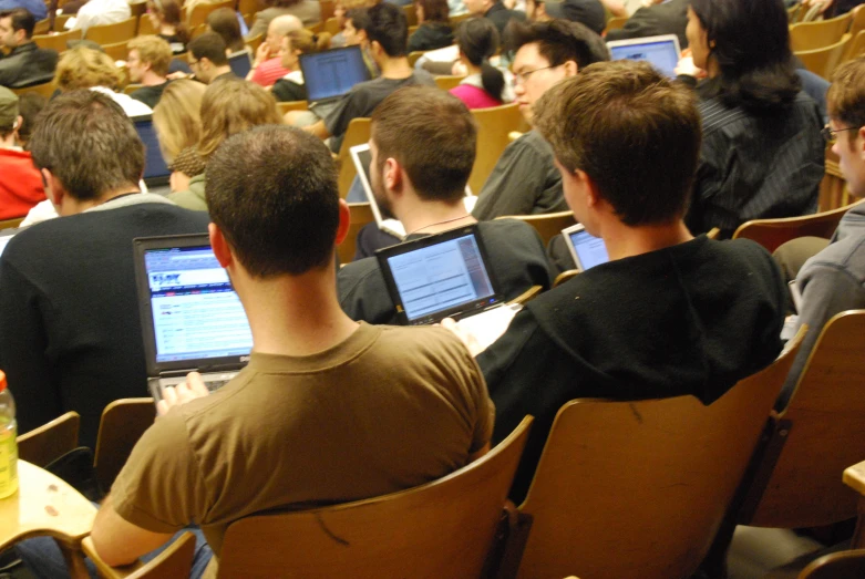 group of people at desks in a lecture hall with their computers