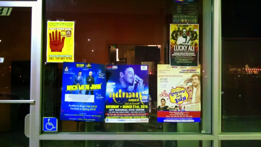 many posters are posted in a window of a business