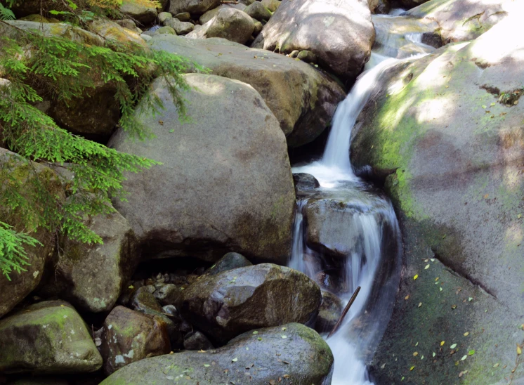 a stream flows over the top of large boulders