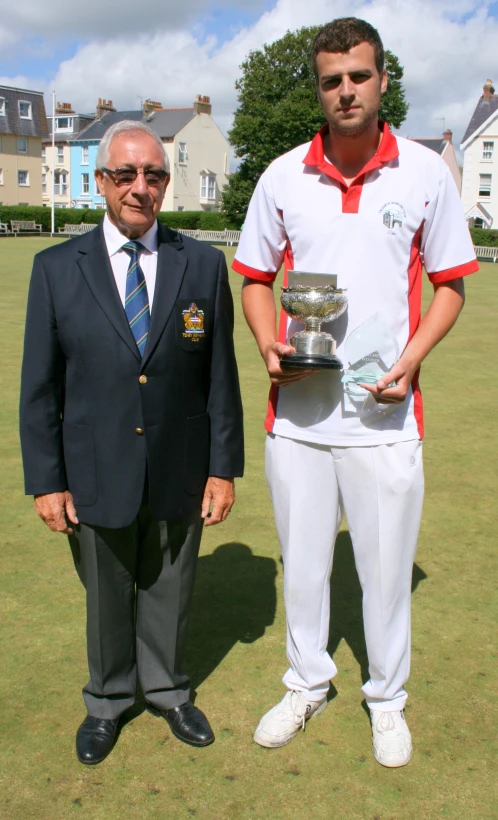 a couple of men stand by a trophy